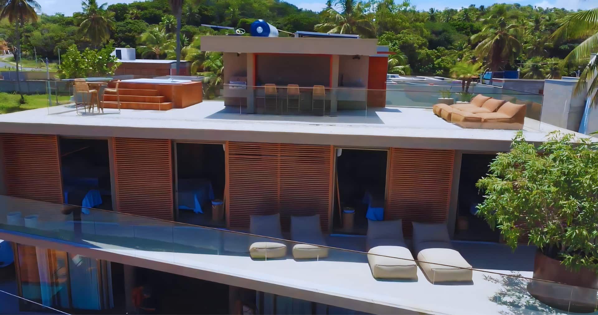 Vista elevada da Casa Pérola mostrando o rooftop com hidromassagem e os brises de madeira das suítes