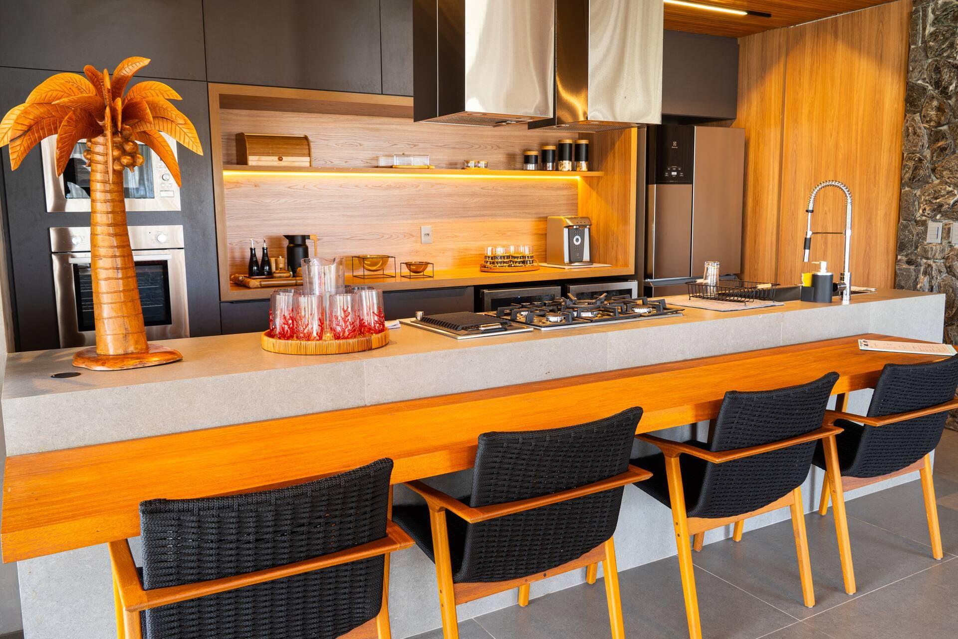 Cozinha da Casa Pérola com ilha central, banquetas e marcenaria em madeira clara