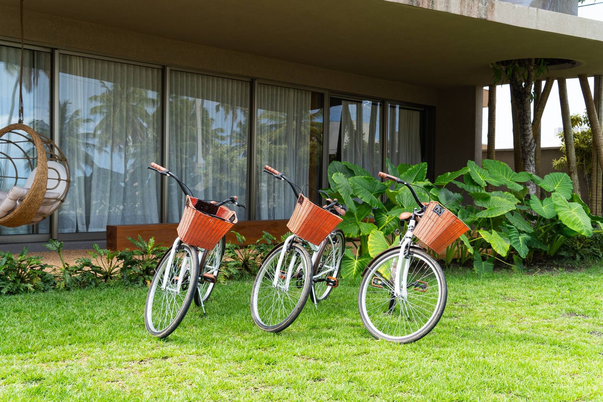 Três bicicletas com cestos apoiadas no gramado do jardim da Casa Pérola