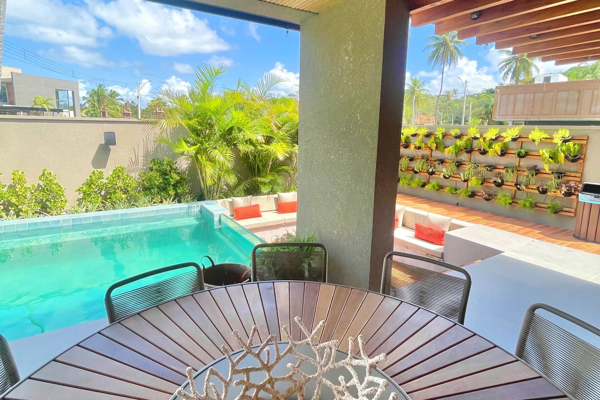 Piscina vista da varanda coberta, com jardim vertical e deck de madeira